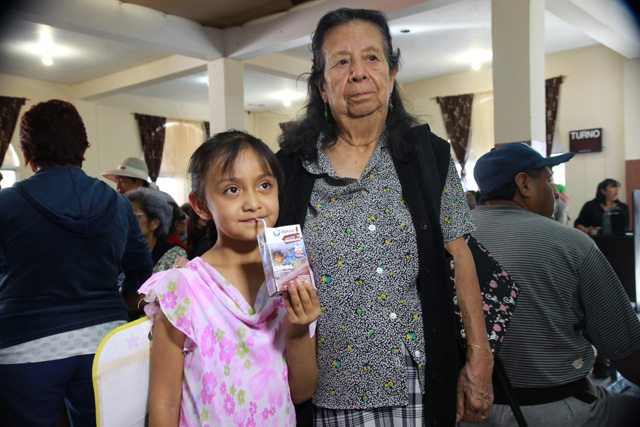 Mujer mayor y niña con un cuartito de leche